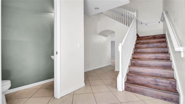 2167 Velvet Leaf Dr, Ocoee, FL 34761 - staircase featuring tile patterned floors, arched walkways, and baseboards