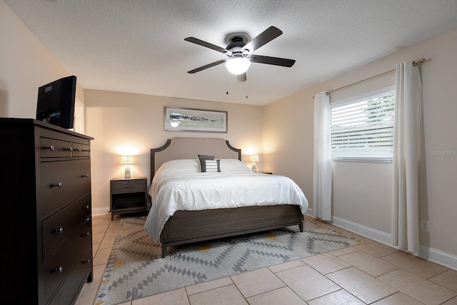 bedroom featuring light tile patterned floors, baseboards, a ceiling fan, and a textured ceiling