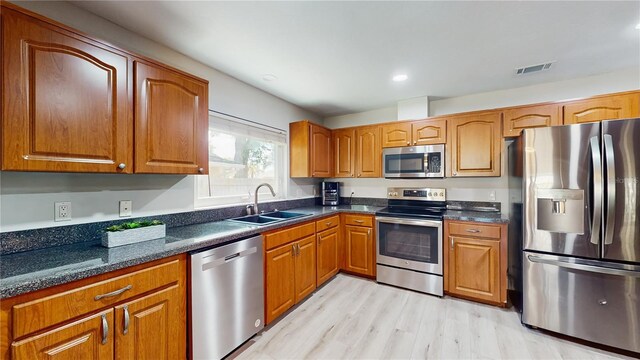 7845 Clubhouse Estates Dr, Orlando, FL 32819 - kitchen featuring a sink, brown cabinets, light wood-style floors, stainless steel appliances, and visible vents