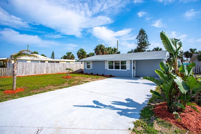 ranch-style home featuring concrete driveway, a front yard, and fence