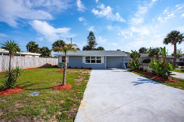 ranch-style house with driveway, fence, and a front lawn