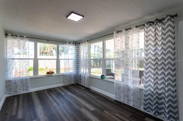 empty room with baseboards, dark wood-style floors, and a textured ceiling