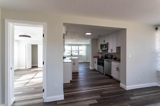 kitchen featuring a textured ceiling, white cabinetry, dark wood finished floors, and stainless steel appliances