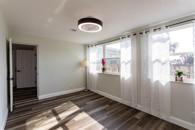 empty room with visible vents, baseboards, and wood finished floors