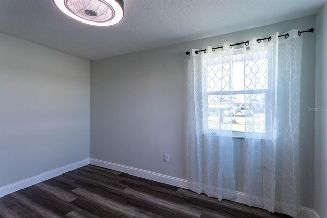 unfurnished room with baseboards and dark wood-style floors