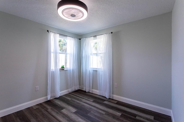 unfurnished room with a textured ceiling, baseboards, and dark wood finished floors