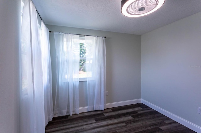 spare room featuring dark wood-style floors, a textured ceiling, and baseboards