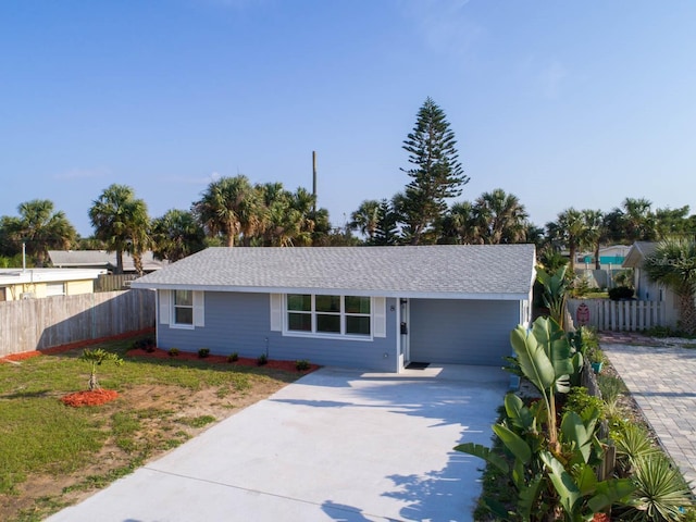 ranch-style house with roof with shingles, concrete driveway, and fence