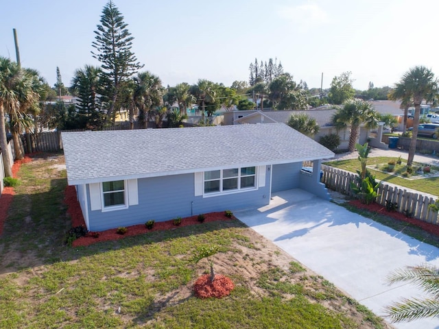 ranch-style house featuring fence, an attached carport, driveway, and roof with shingles