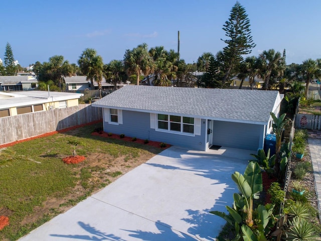 ranch-style home featuring concrete driveway, a front yard, roof with shingles, and fence
