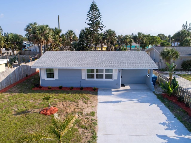 ranch-style house featuring roof with shingles, driveway, fence, and a front lawn