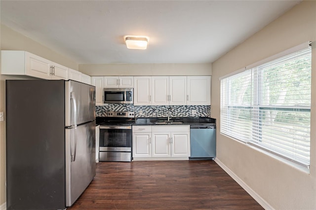 1411 N Powers Dr, Orlando, FL 32818 - kitchen featuring dark countertops, appliances with stainless steel finishes, a sink, and white cabinetry