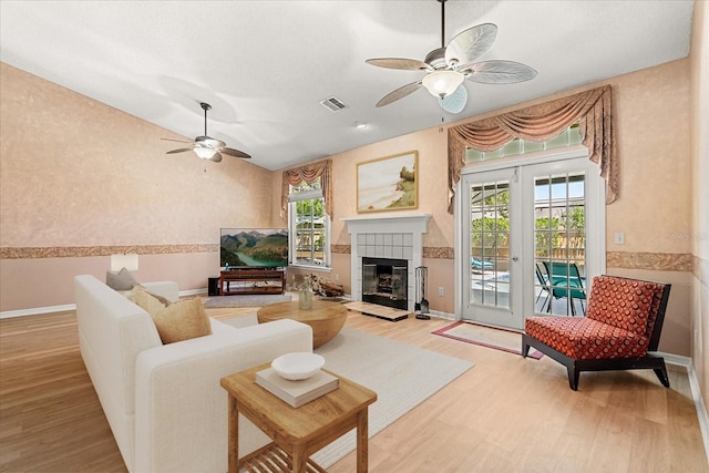 living area with baseboards, a ceiling fan, visible vents, and light wood-style flooring