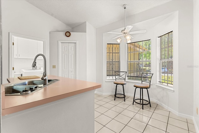 kitchen featuring light countertops, a sink, ceiling fan, and light tile patterned flooring