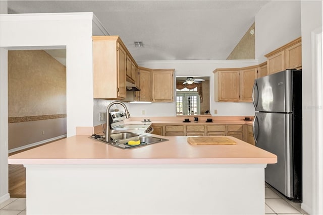 kitchen featuring stainless steel appliances, a peninsula, a sink, light countertops, and light tile patterned floors