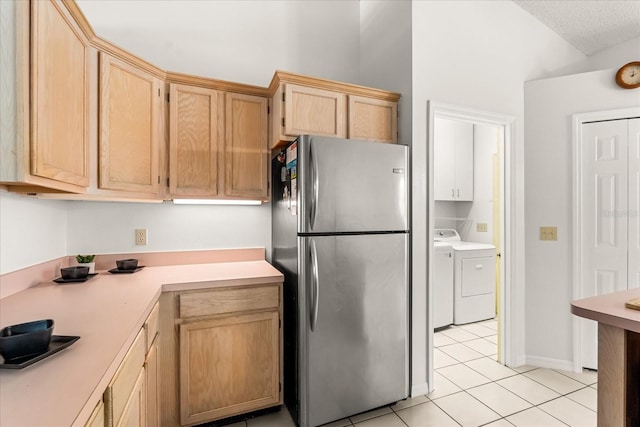 kitchen featuring light brown cabinets, light tile patterned floors, light countertops, washing machine and dryer, and freestanding refrigerator