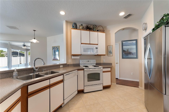 kitchen featuring visible vents, white appliances, a sink, and white cabinetry
