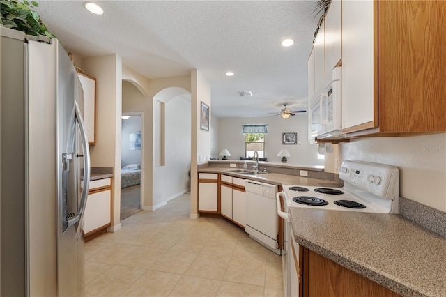 kitchen with a sink, a textured ceiling, white appliances, arched walkways, and recessed lighting