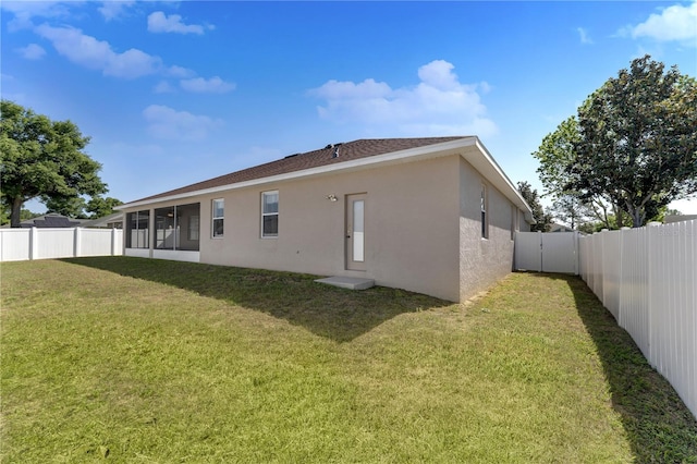 rear view of property featuring stucco siding, a sunroom, a yard, and a fenced backyard