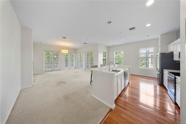 kitchen featuring a sink, open floor plan, white cabinetry, baseboards, and appliances with stainless steel finishes