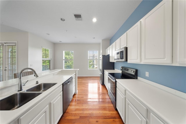 kitchen with visible vents, a sink, light wood-style flooring, appliances with stainless steel finishes, and white cabinetry