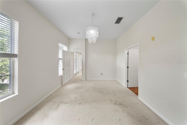 unfurnished room featuring an inviting chandelier, carpet flooring, visible vents, and baseboards