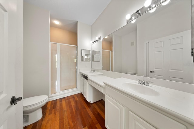 bathroom featuring a sink, a shower stall, double vanity, and toilet