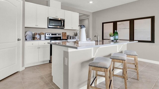 2690 Trinidad Rd, Haines City, FL 33844 - kitchen featuring appliances with stainless steel finishes, light tile patterned floors, white cabinets, and a breakfast bar