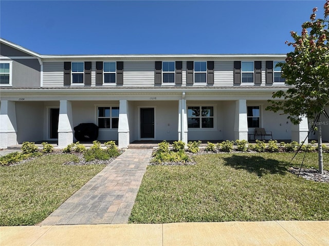 view of front of house featuring a porch, stucco siding, and a front lawn