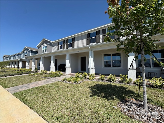 view of front of house featuring a front yard, a porch, and stucco siding
