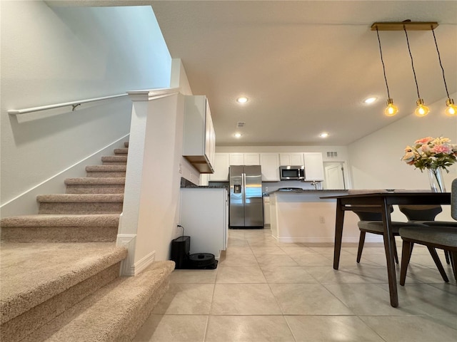 kitchen with decorative light fixtures, appliances with stainless steel finishes, dark countertops, and white cabinetry