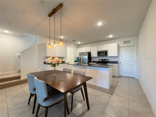 kitchen featuring light tile patterned floors, white cabinetry, dark countertops, visible vents, and appliances with stainless steel finishes