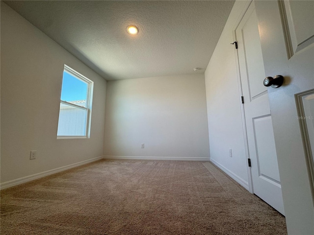 unfurnished room featuring a textured ceiling, baseboards, and light carpet