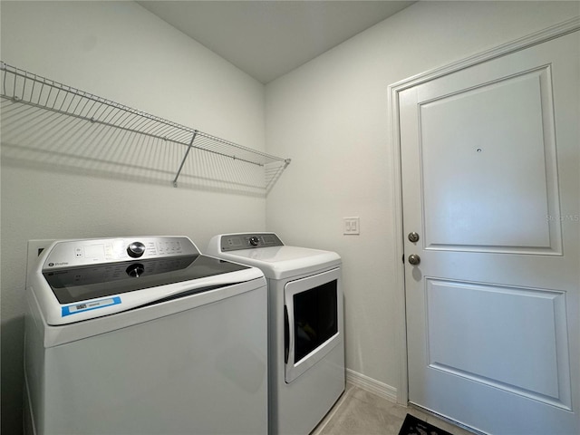 washroom with baseboards, separate washer and dryer, and laundry area