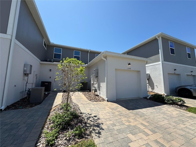 view of front of home featuring stucco siding, cooling unit, decorative driveway, and an attached garage