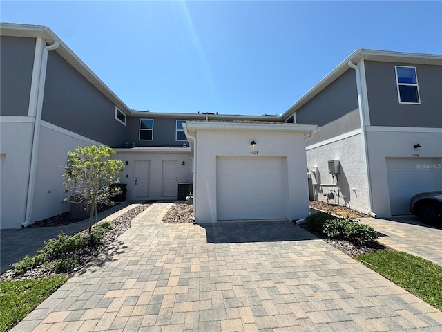 multi unit property featuring central AC, a garage, stucco siding, and decorative driveway