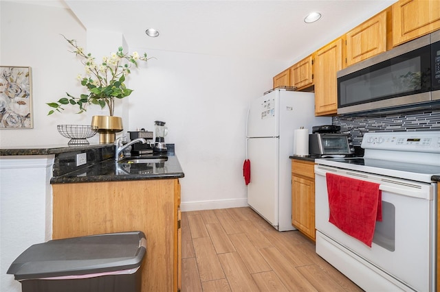 4011 Venetian Bay Dr Unit 103, Kissimmee, FL 34741 - kitchen with baseboards, a sink, white appliances, light wood-style flooring, and decorative backsplash
