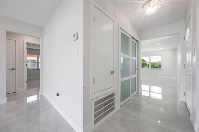 hallway featuring marble finish floor, baseboards, and visible vents