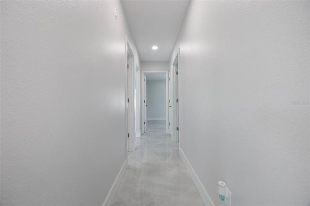 corridor featuring recessed lighting, marble finish floor, and baseboards