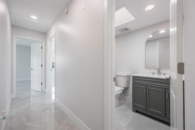 half bath featuring toilet, visible vents, baseboards, marble finish floor, and vanity