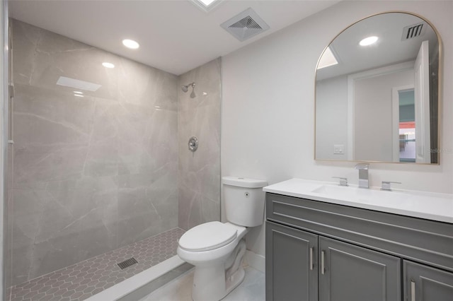 full bathroom with tiled shower, visible vents, vanity, and toilet