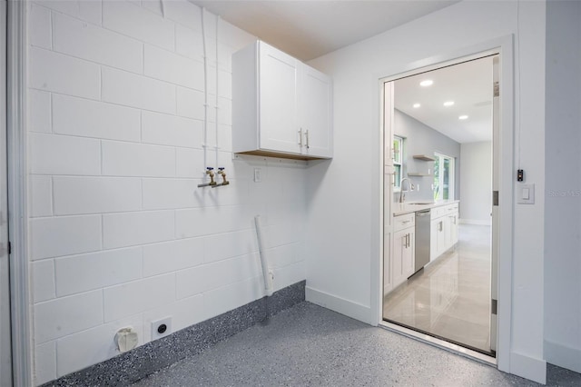 clothes washing area with baseboards, a sink, and recessed lighting