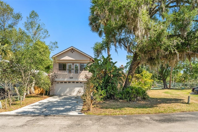 view of front of house featuring a balcony, stucco siding, an attached garage, driveway, and a front yard