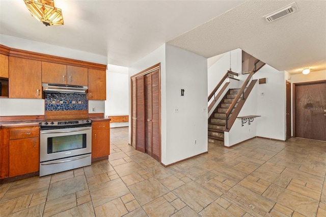 kitchen with visible vents, brown cabinetry, under cabinet range hood, and stainless steel range with electric stovetop