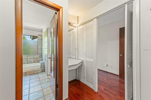 hall with wood finished floors and a textured ceiling