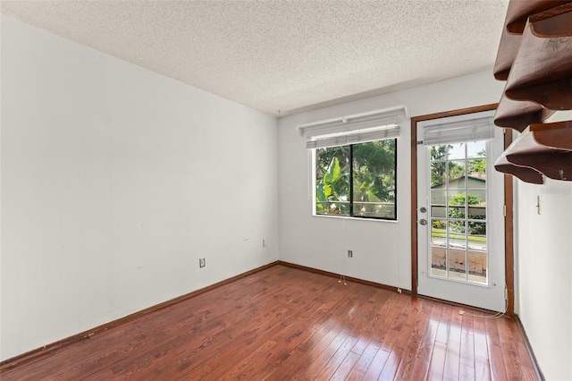 empty room with hardwood / wood-style flooring, baseboards, and a textured ceiling