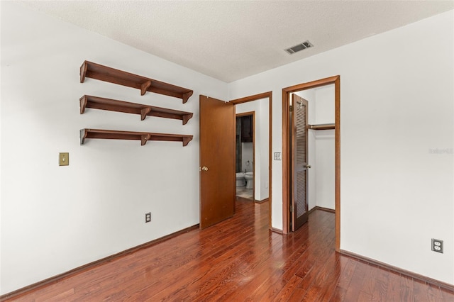 spare room with baseboards, visible vents, hardwood / wood-style floors, and a textured ceiling