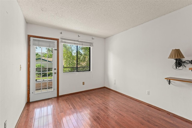 empty room featuring hardwood / wood-style floors, baseboards, and a textured ceiling