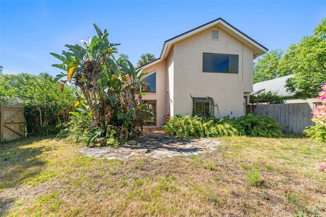 back of property with fence private yard, a lawn, and stucco siding