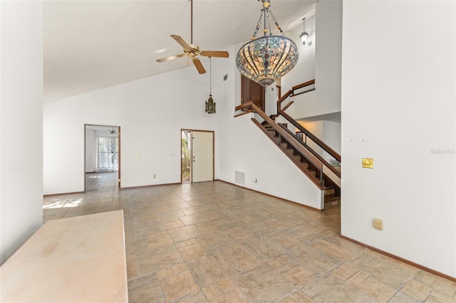 unfurnished living room featuring stairway, baseboards, high vaulted ceiling, and ceiling fan